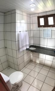 a white tiled bathroom with a toilet and a sink at Recreio das Fontes in Beberibe