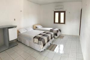 Duas camas num quarto branco com lareira em Recreio das Fontes em Beberibe