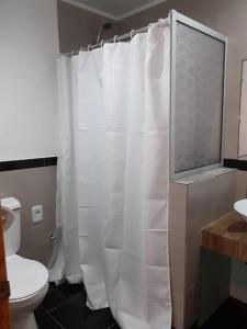 uma casa de banho com uma cortina de chuveiro branca e um WC. em Complejo 421 em Piriápolis