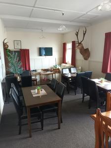 Ahaura Hotel في غرايموث: غرفة طعام مع طاولات وكراسي وغرفة معيشة