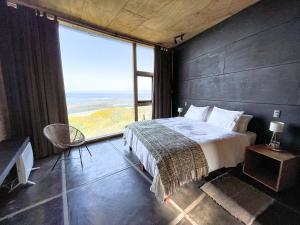 a bedroom with a large bed and a large window at El Coo Lodge in Queilén