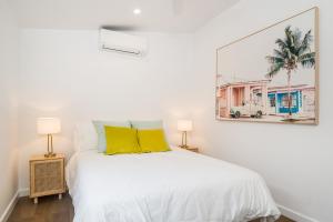 a white bedroom with a white bed with yellow pillows at Espadrille Casita in Byron Bay