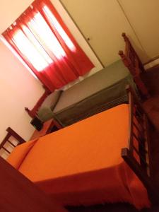 a bedroom with an orange bed and a window at La Casa de la Parra in Villa Carlos Paz