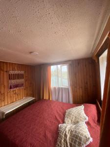 a bedroom with a red bed with a window at Mi casa chilota in Ancud