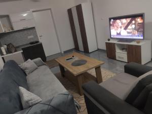 NEER في Živinice: غرفة معيشة مع أريكة وطاولة وتلفزيون