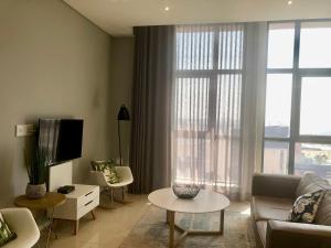 uma sala de estar com um sofá e uma televisão em Urban Awe Apartment: iTowers 21st Floor em Gaborone