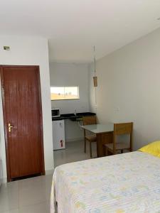 1 dormitorio con cama, mesa y cocina en Lavínia loft 2, en Búzios