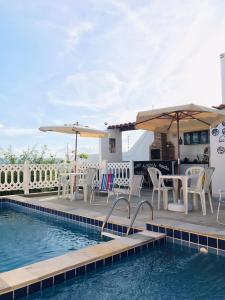 a pool with tables and chairs and umbrellas at Flat Rainha da Serra in Bezerros