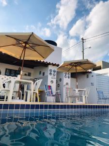 a group of chairs and umbrellas next to a swimming pool at Flat Rainha da Serra in Bezerros