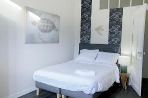 - une chambre dotée d'un lit avec des draps blancs et une photo dans l'établissement Le 34 Malon, T5 hypercentre chic et cosy, wifi, netflix par SOVALFI, à Saint-Étienne
