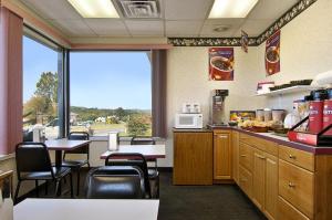 un restaurante con mesas y sillas y una cocina con vistas en Travelodge by Wyndham Ridgeway Martinsville Area, en Martinsville