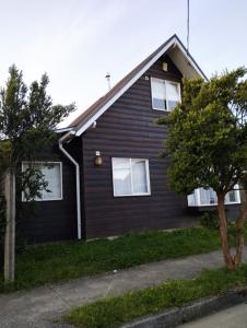 una casa negra con ventanas blancas y árboles en Casa de la Ribera Pelantaro, en Valdivia