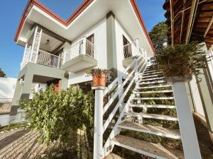 a white house with stairs and potted plants at Casa Garitas GuestHouse - Free SJO Airport Shuttle in Santiago Este