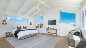 a white bedroom with a bed and a chair at Warrahwillah in Currarong