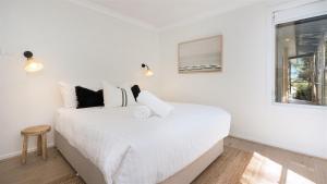 a white bedroom with a large bed and a window at Warrahwillah in Currarong +34 photos