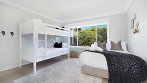 a bedroom with a white bunk bed and a window at Warrahwillah in Currarong