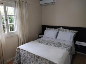 1 dormitorio con 1 cama con sábanas blancas y ventana en Casa Matriz Palace, en Canela