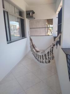 a hanging hammock in a room with windows at Kitnet Itapuã in Vila Velha