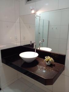 La salle de bains est pourvue de 2 lavabos et d'un grand miroir. dans l'établissement Kitnet Itapuã, à Vila Velha