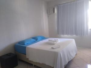 ein Schlafzimmer mit einem Bett mit blauen Kissen und einem Tisch in der Unterkunft Kitnet Itapuã in Vila Velha