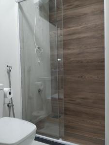 La salle de bains est pourvue d'une douche avec une porte en verre. dans l'établissement A Pousadinha, à Águas de São Pedro