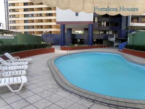 a large swimming pool with chairs next to a building at Porto de Iracema - Fortaleza houses in Fortaleza