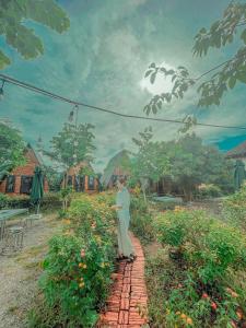 a woman standing on a brick path in a field of flowers at Homestay Bình Huy in Mộc Châu