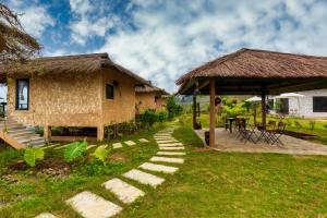 een huis met een rieten dak en een grasveld bij Sapa Farmstay in Sa Pa