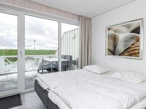a white bedroom with a bed and a balcony at Two-Bedroom Holiday home in Wendtorf 1 in Wendtorf