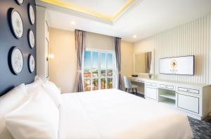 a bedroom with a bed and a desk and a television at Eastin Hotel Vientiane in Vientiane