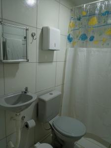 y baño con aseo, lavamanos y cortina de ducha. en Pousada da Sônia en Camaragibe