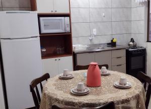 een keuken met een tafel met een rode kruik erop bij Dom joaquim in Imbituba