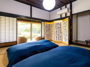 a bedroom with a blue bed in a room with windows at さいの郷「椛」 in Kagamino
