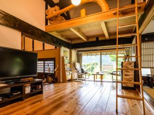a living room with wooden floors and a large television at さいの郷「椛」 in Kagamino