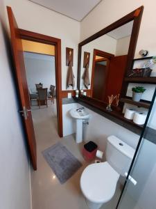 een badkamer met een toilet, een wastafel en een spiegel bij Apartamento Novo Norte da Ilha in Florianópolis