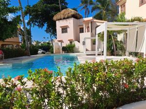 a villa with a swimming pool in front of a house at Beach Villas & Apartments Larimar in Punta Cana