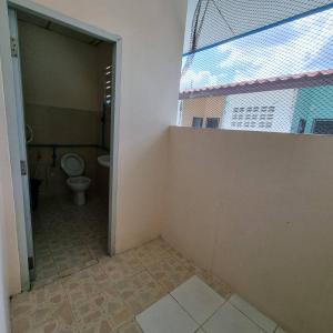 un baño vacío con aseo y ventana en Sorworakit Hotel, en Bang Saen