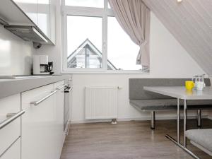 a white kitchen with a table and a window at Holiday Home Strandblick II in Wendtorf