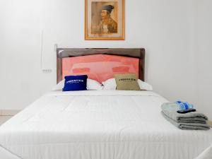 Urbanview Hotel Rio Life House Cianjur by RedDoorz في سيانجور: غرفة نوم بسرير أبيض مع صورة على الحائط
