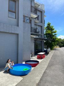 宜蘭市的住宿－Chill鬆口氣-包棟民宿，坐在建筑物前的游泳池里的女人和婴儿