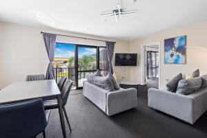 ASURE Rotorua International Motor Inn في روتوروا: غرفة معيشة مع طاولة وكراسي وغرفة طعام