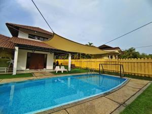 a swimming pool in front of a house with a fence at Melaka AFamosa Pool Villa The Moments Villa Lot 1319 Homestay in Kampong Pulau Sebang