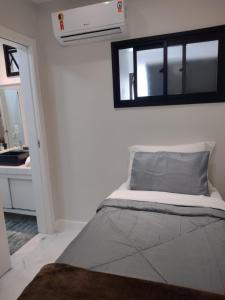 Cama en habitación con ventana y lavabo en Vista relaxante - Apartamento no centrinho de Guarapari tranquilo e confortável, en Guarapari