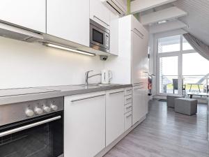 a white kitchen with a sink and a microwave at 6 person holiday home in Wendtorf in Wendtorf +7 photos
