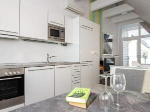 eine Küche mit weißen Schränken und einem Tisch mit einem Glas Wein in der Unterkunft 6 person holiday home in Wendtorf in Stein