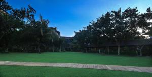 duże zielone pole z drzewami i budynek w obiekcie Lombok Garden Hotel w mieście Mataram