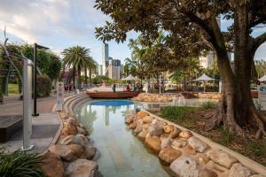 une piscine dans un parc avec un arbre et des rochers dans l'établissement Southbank Heart+2 Bed+Balcony+Pool+Gym+Free Wifi, à Brisbane