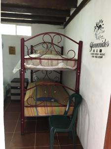 Ce lit superposé se trouve dans un dortoir doté d'une chaise verte. dans l'établissement Hostal San Andrés de k-noa, à Canoa