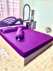 a large bed with a purple comforter in a bedroom at Ramizu Homestay Pokok Sena in Pokok Sena