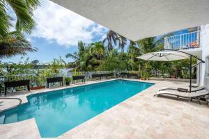 einen Pool mit Stühlen und einem Sonnenschirm in der Unterkunft Lakefront Duplex with Pool between Miami & Florida Keys 4 Bedroom 2 Bathroom in Cutler Bay